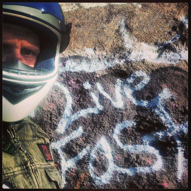 motorcyle rider in front of grafitti