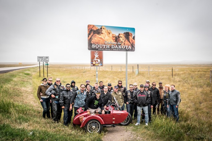 veterans stand in front of sign with motorcycle sidecar