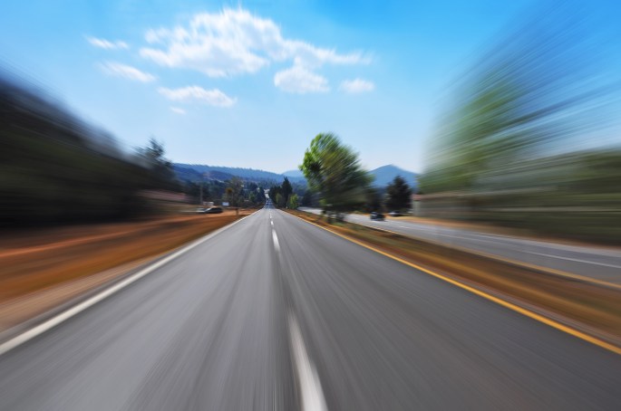 a road leads to the horizon, blurred with speed