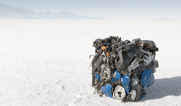 A Buell motorcycle in the desert on a dry lake bed, crushed into a cube
