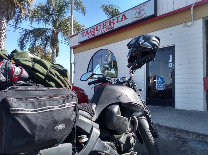 buell motorcycle with saddlebags parked in front of a taco restaurant