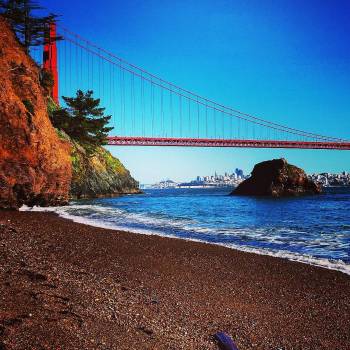 San Francisco Bay shore with golden gate bridge and city skyline, beach shoreline and cloudless sky