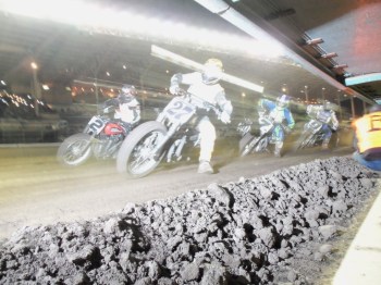 flat track racing motorcycles passing at high speed with motion blur