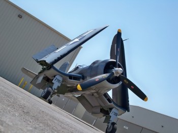f4u corsair world war 2 warbird waiting with wings folded hangers and sky background