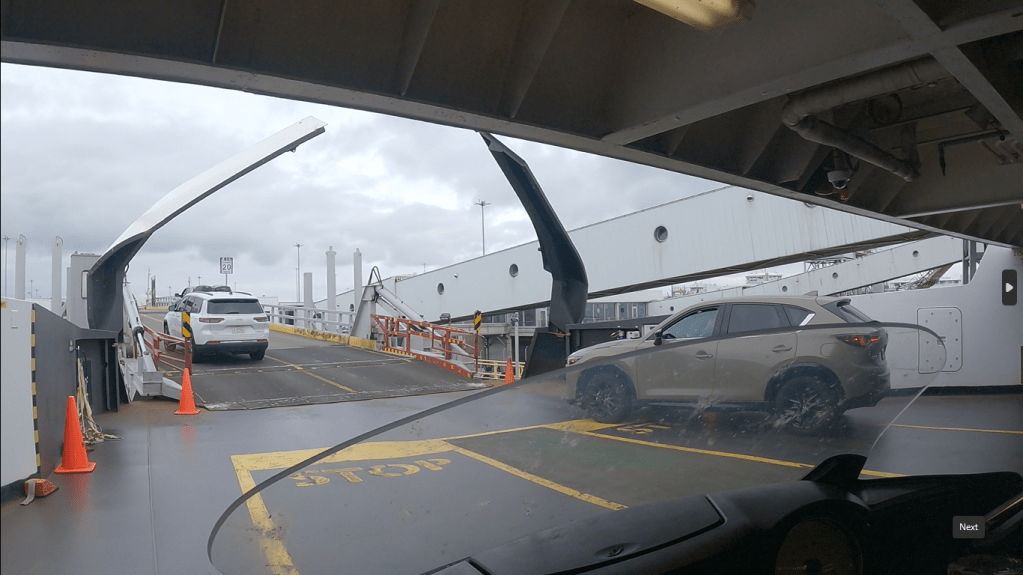 pov of a motorcyclist exiting the middle decks of a ferry with other vehicles, about to mount the exit ramp