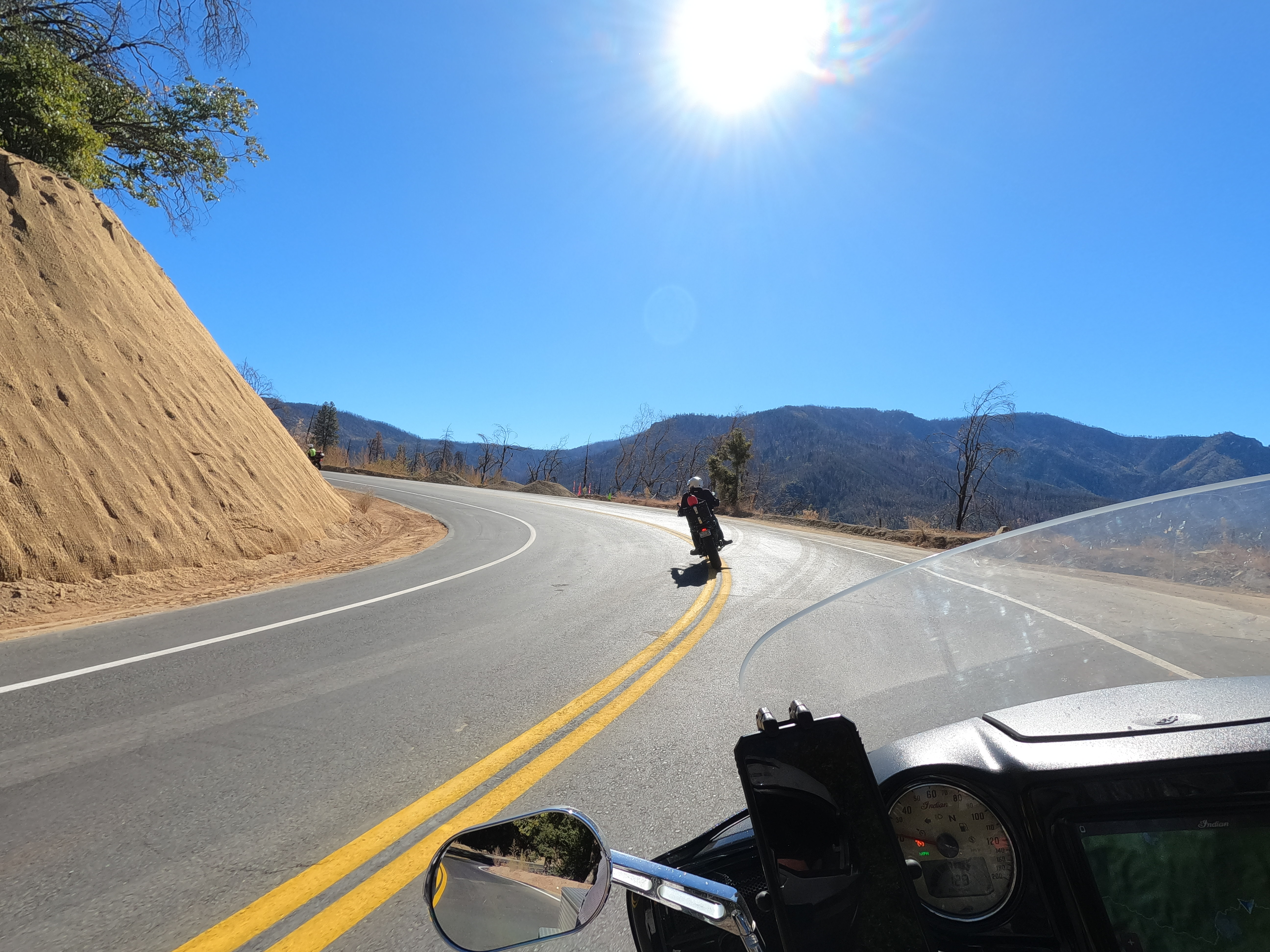POV of motorcyclist following other rider through mountain curve, crossing double yellow paint line