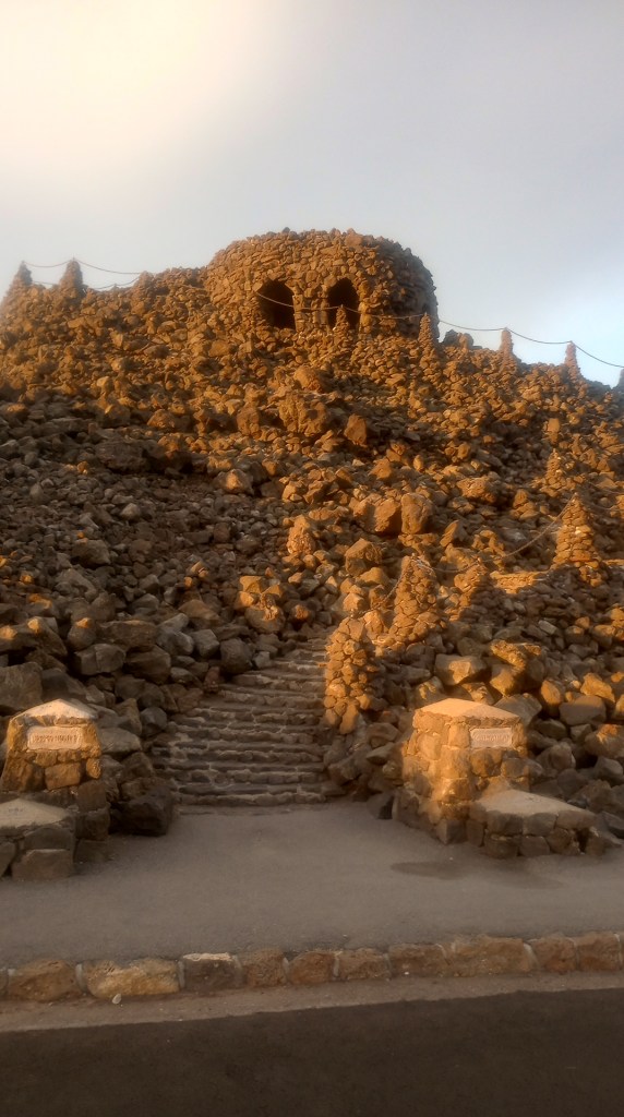 The Dee Wright Observatory, a round rock building with a flat roof for observation, surrounded by lave rock and a staircase