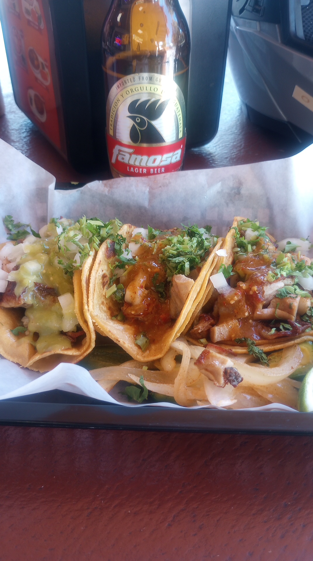 three buche tacos in a basket with Mexican beer bottle in background