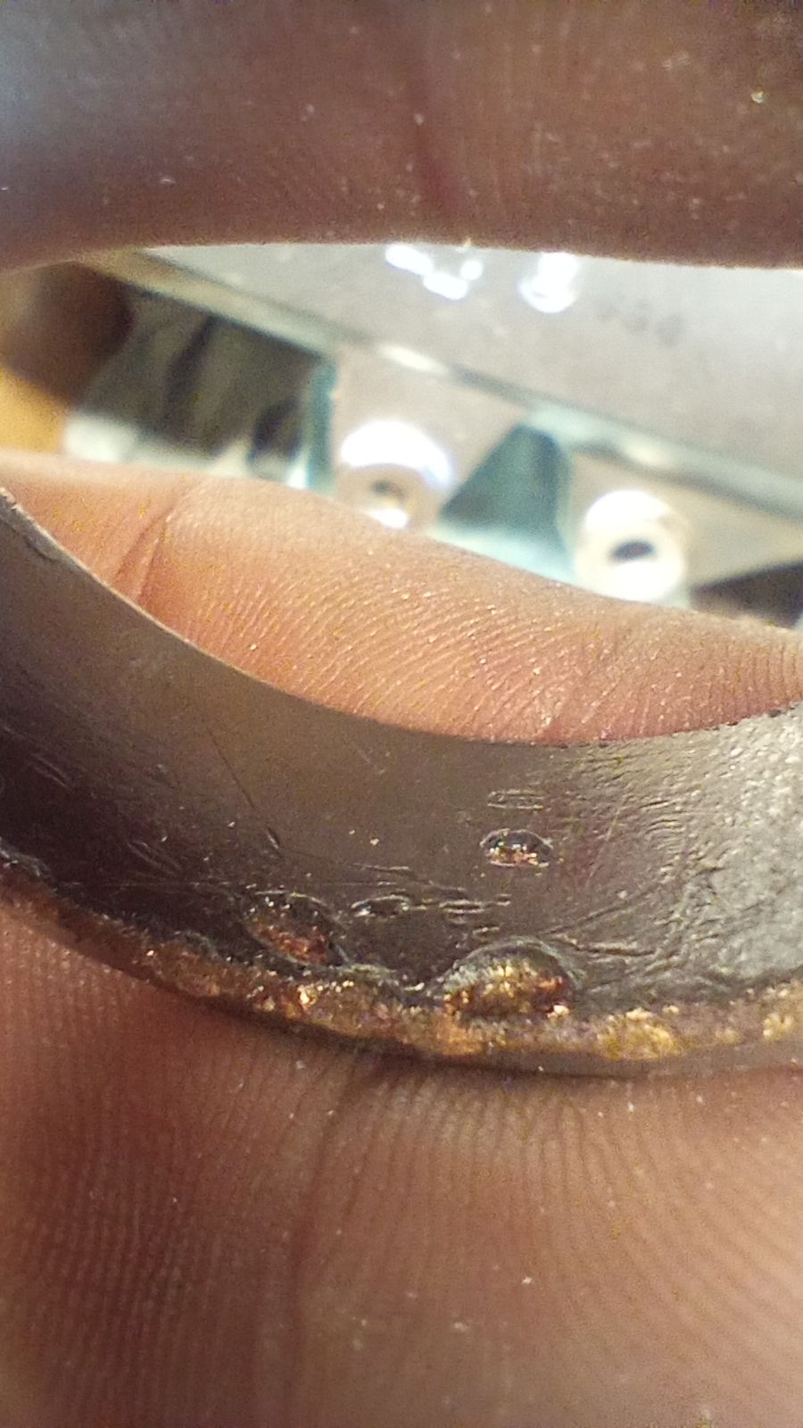 close up of a damaged suspension bushing, its Teflon coating marred with peen marks