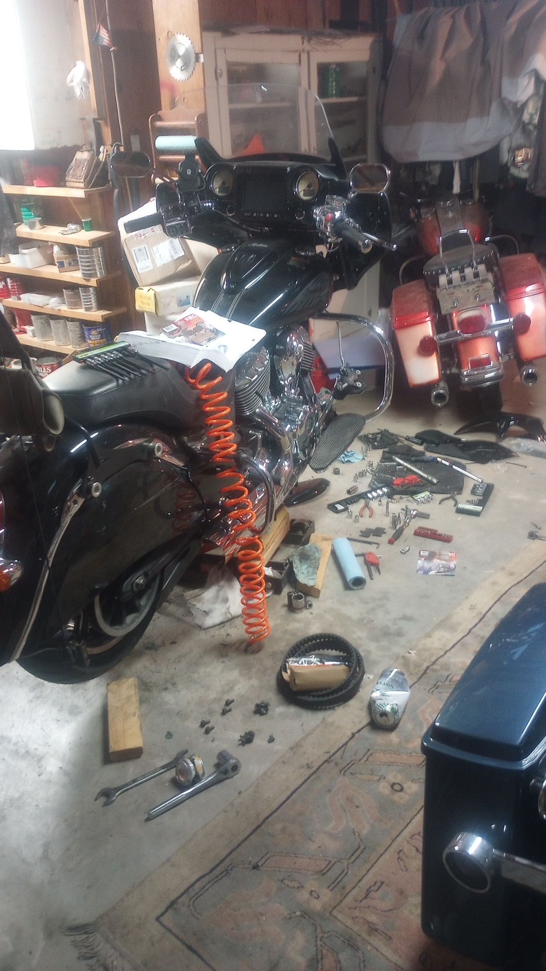 a Chieftain motorcycle on a maintenance life with dozens of tools scattered on the concrete floor below it