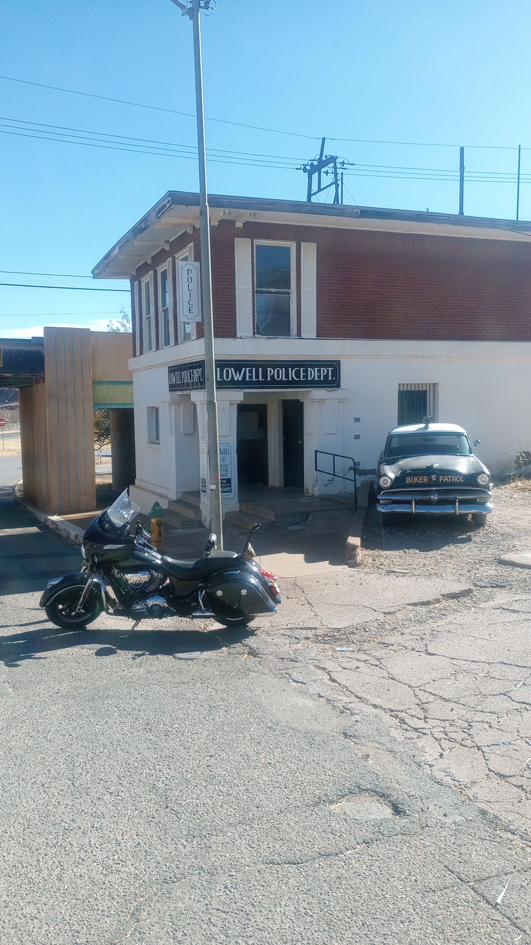 street scene in Lowell, Arizona. The mock police department and a 1950's era police car, with an Indian CHieftain Motorcycle in front of them