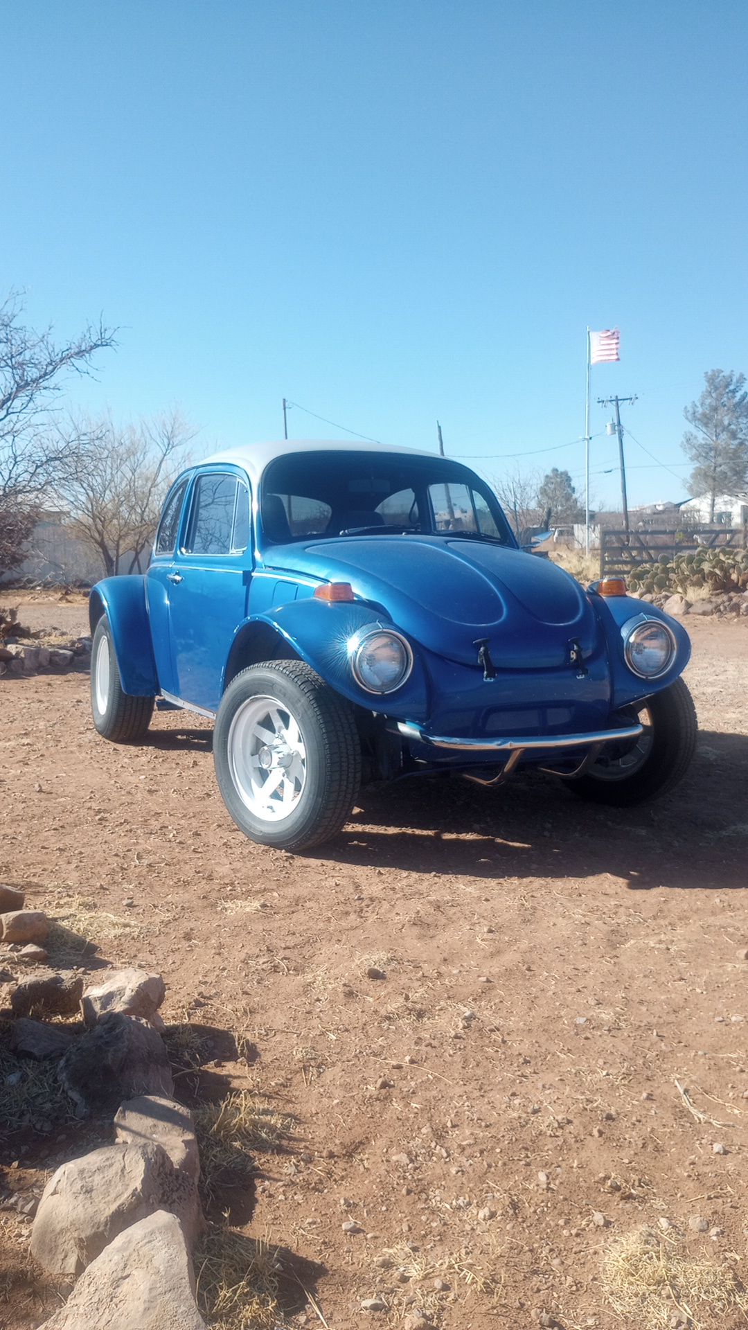a blue VW Baja Bug parked in a desert setting