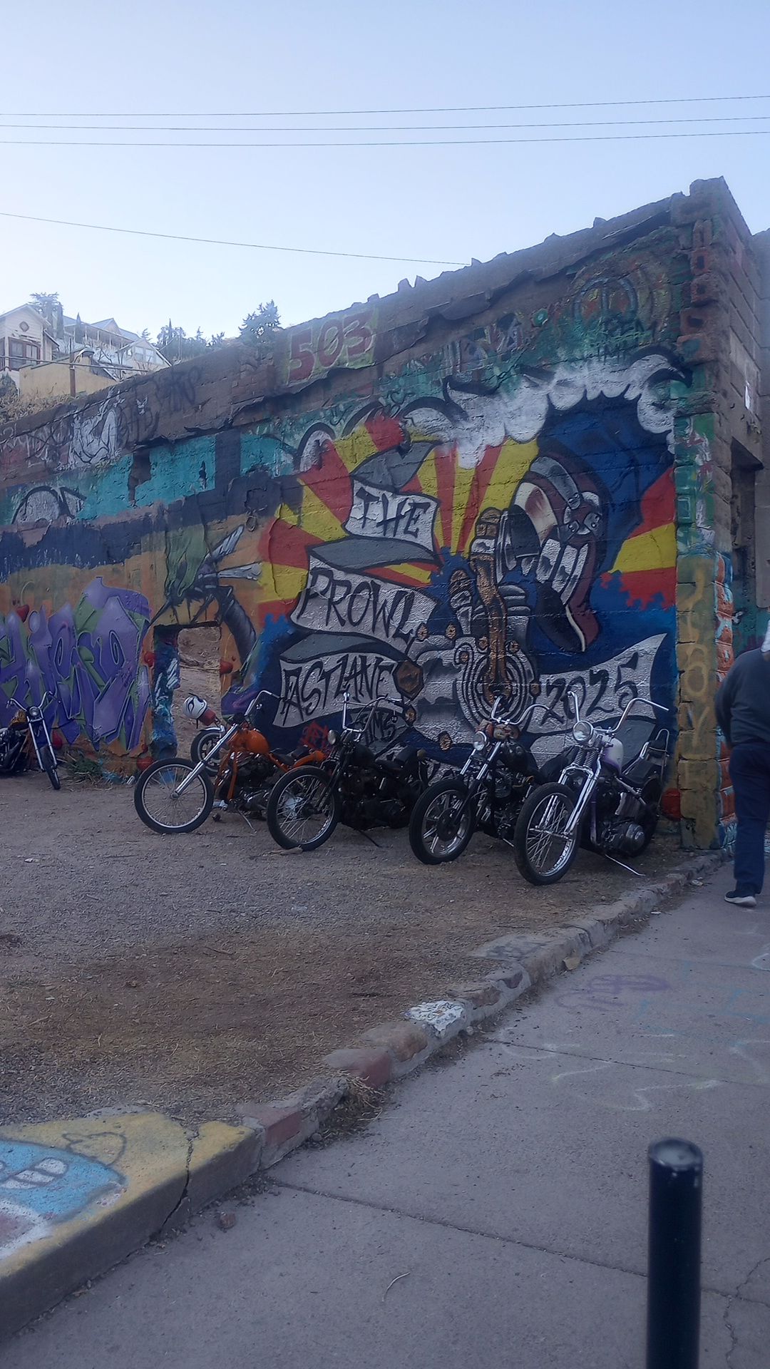 Harley chopper motorcycles parked against an old wall with graffiti on it in Brewery Gultch, Bisbee Arizona