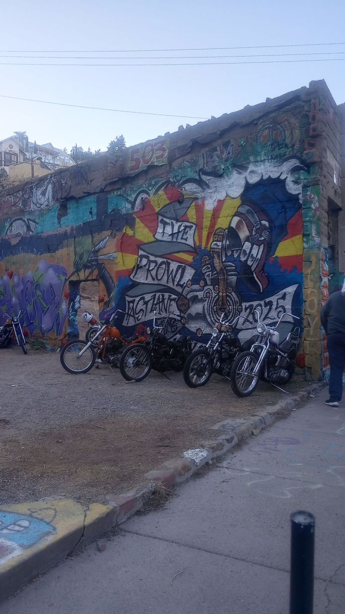 Harley chopper motorcycles parked against an old wall with graffiti on it in Brewery Gultch, Bisbee Arizona