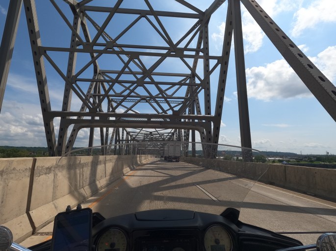 POV of a motorcyclist crossing a steel truss bridge