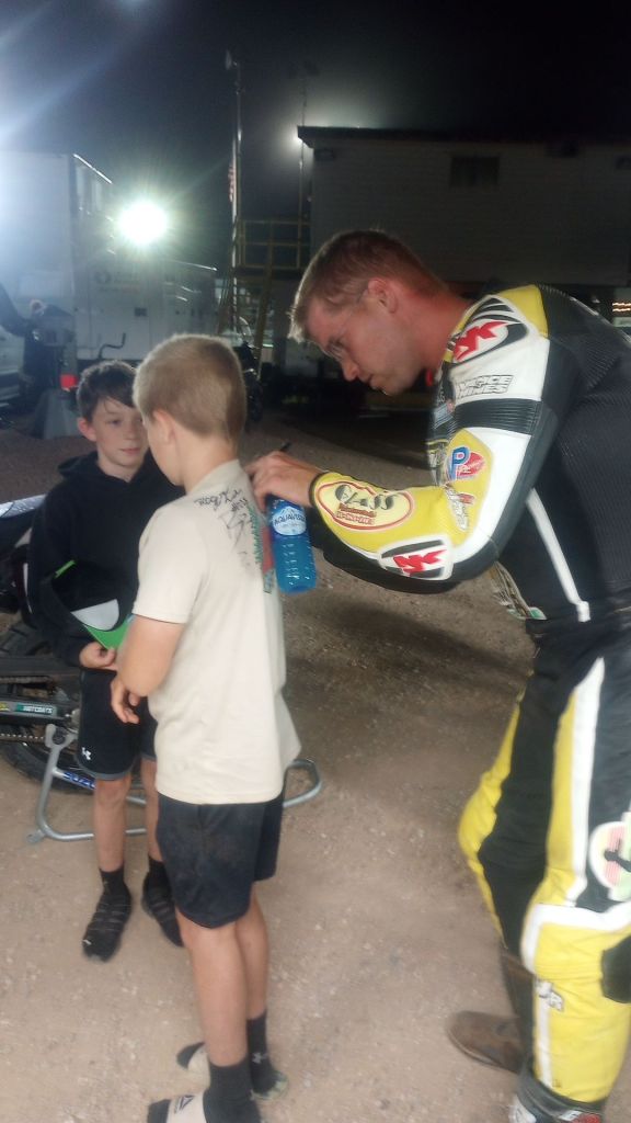racer dan bromley signing a young fan's t-shirt