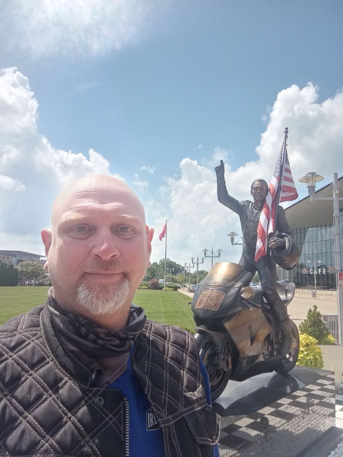 JOhn Killmore standing in front of a memmorial statue to Nicky Hayden in Owensboro Kentucky