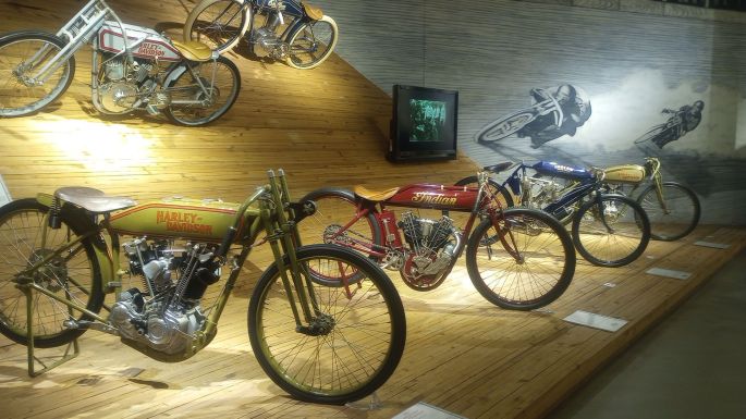 Board track racing motorcycle on a backlit display simulating the banked board tracks of the 1920's