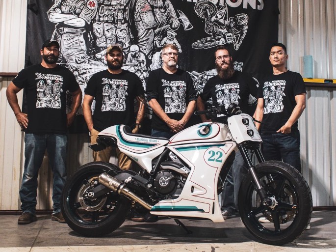 motorcycle missions volunteers and participants pose in front of a while custom motorcycle they have built