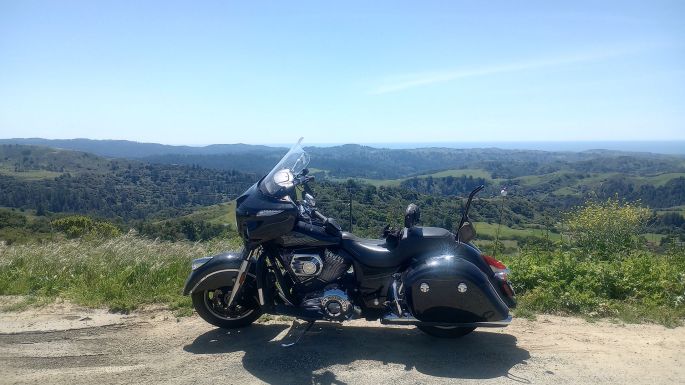 An Indian CHieftain touring motorcycle parked roadside, overlooking lush greenery and rolling hills of coastal California, along Skyline bouldevard in the San Francisco south bay area.