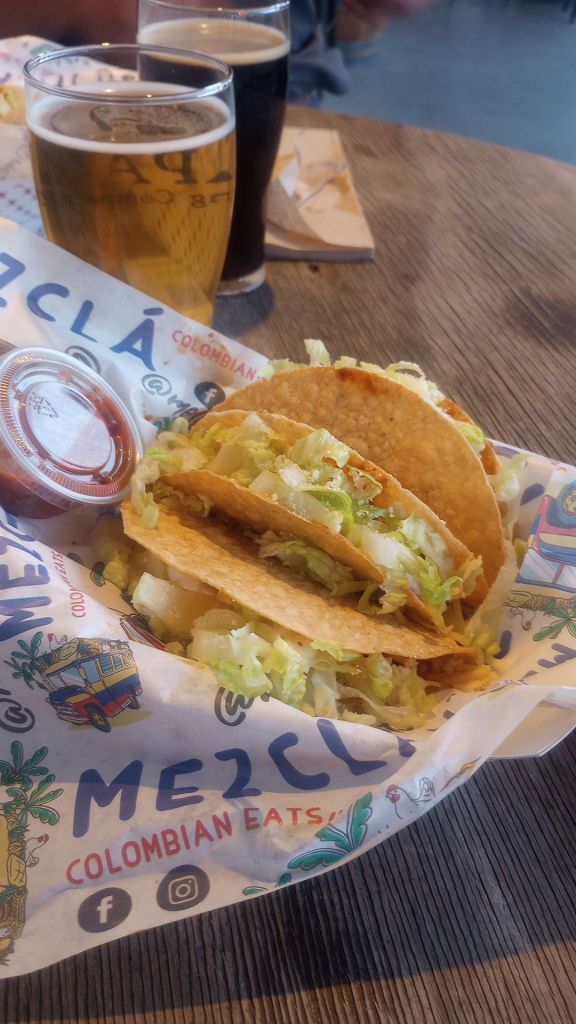 hard shell tacos in a basket with salsa and a wax paper base